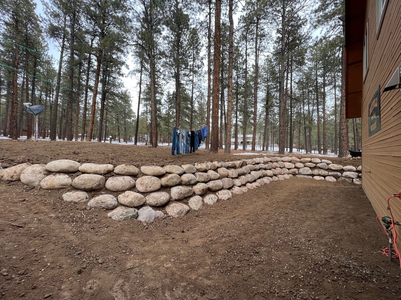 Backyard boulder retaining wall in a pine forest setting in Durango, Colorado