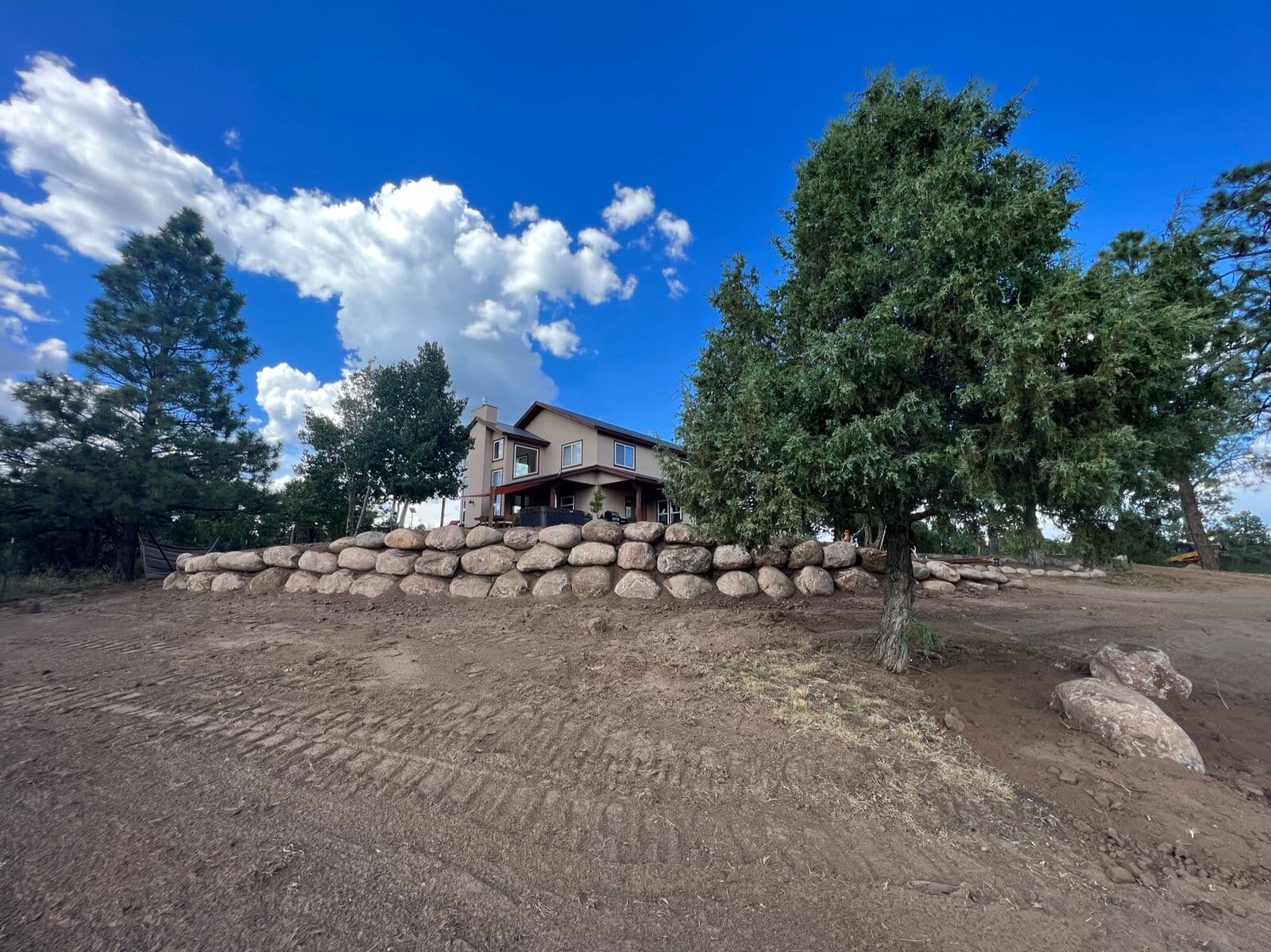 Boulder retaining wall surrounding a hilltop home near Durango, Colorado by LandEx Earthworks