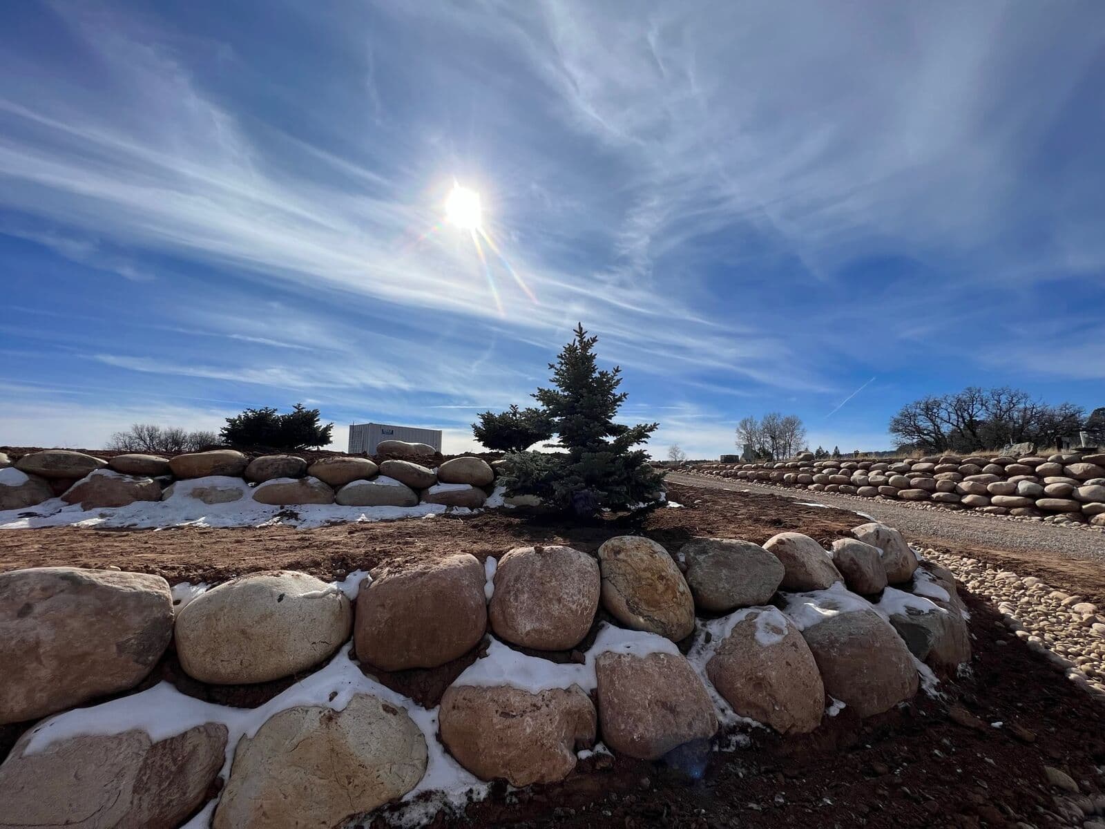 Boulder retaining wall construction in winter on a Durango, Colorado property