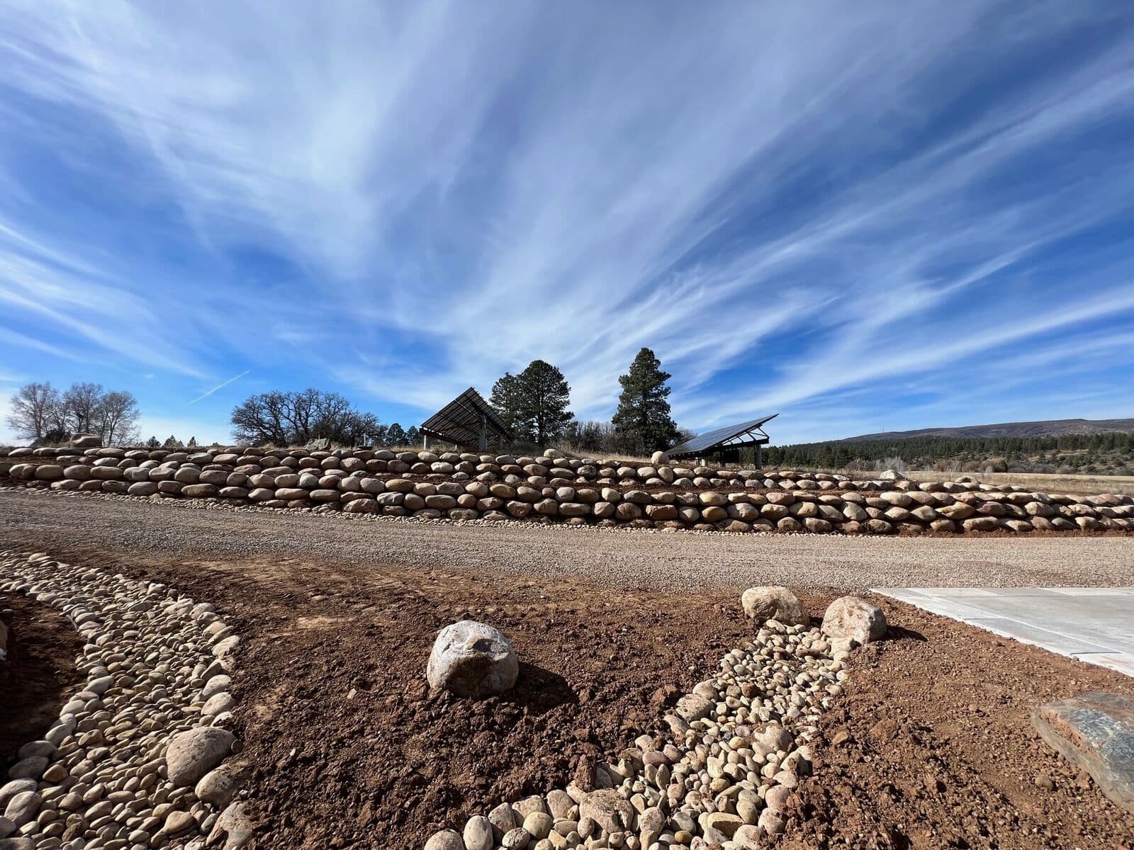 Long boulder retaining wall and gravel pathway on a mountain property in Southwest Colorado
