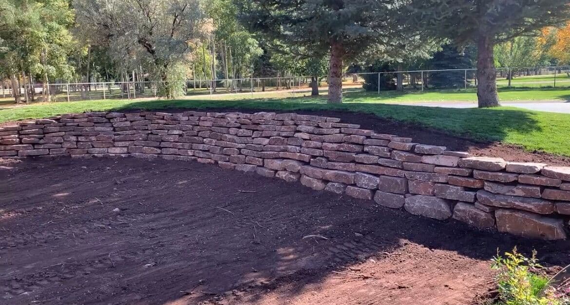 Curved stacked stone retaining wall built in Durango, Colorado by LandEx Earthworks