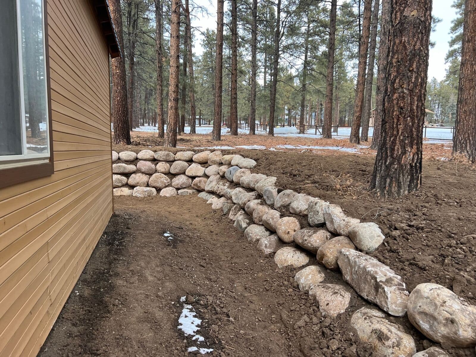 Double row boulder retaining walls beside a mountain home in Durango, Colorado by LandEx Earthworks