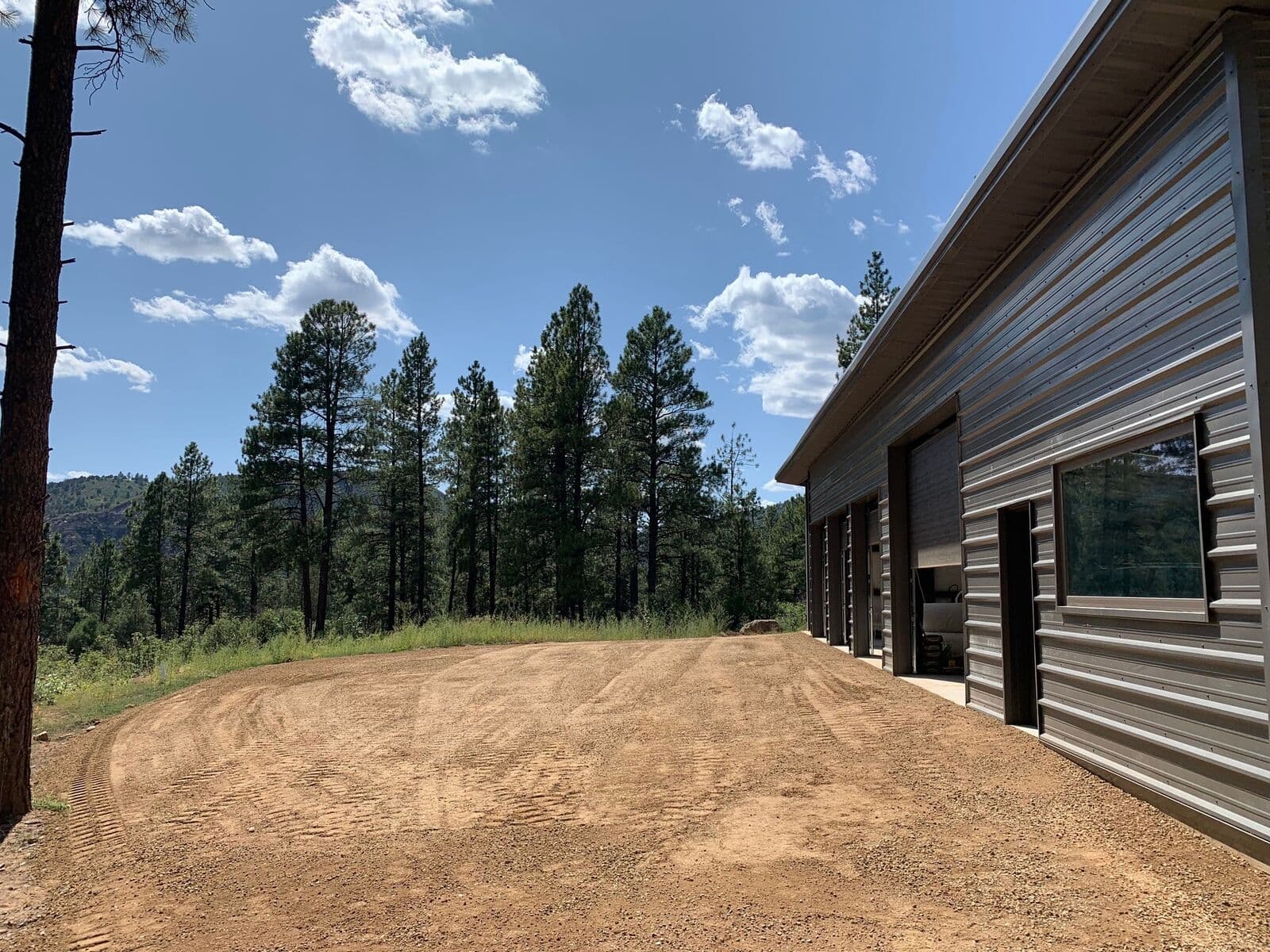 Finish grading around a metal shop building on a forested lot in Durango, Colorado