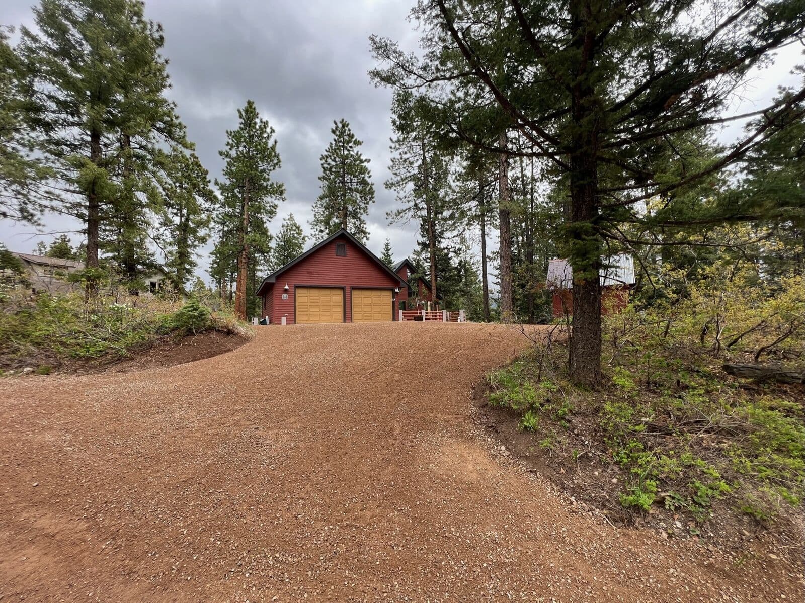 Gravel driveway leading to a red barn on a forested property in Durango, Colorado