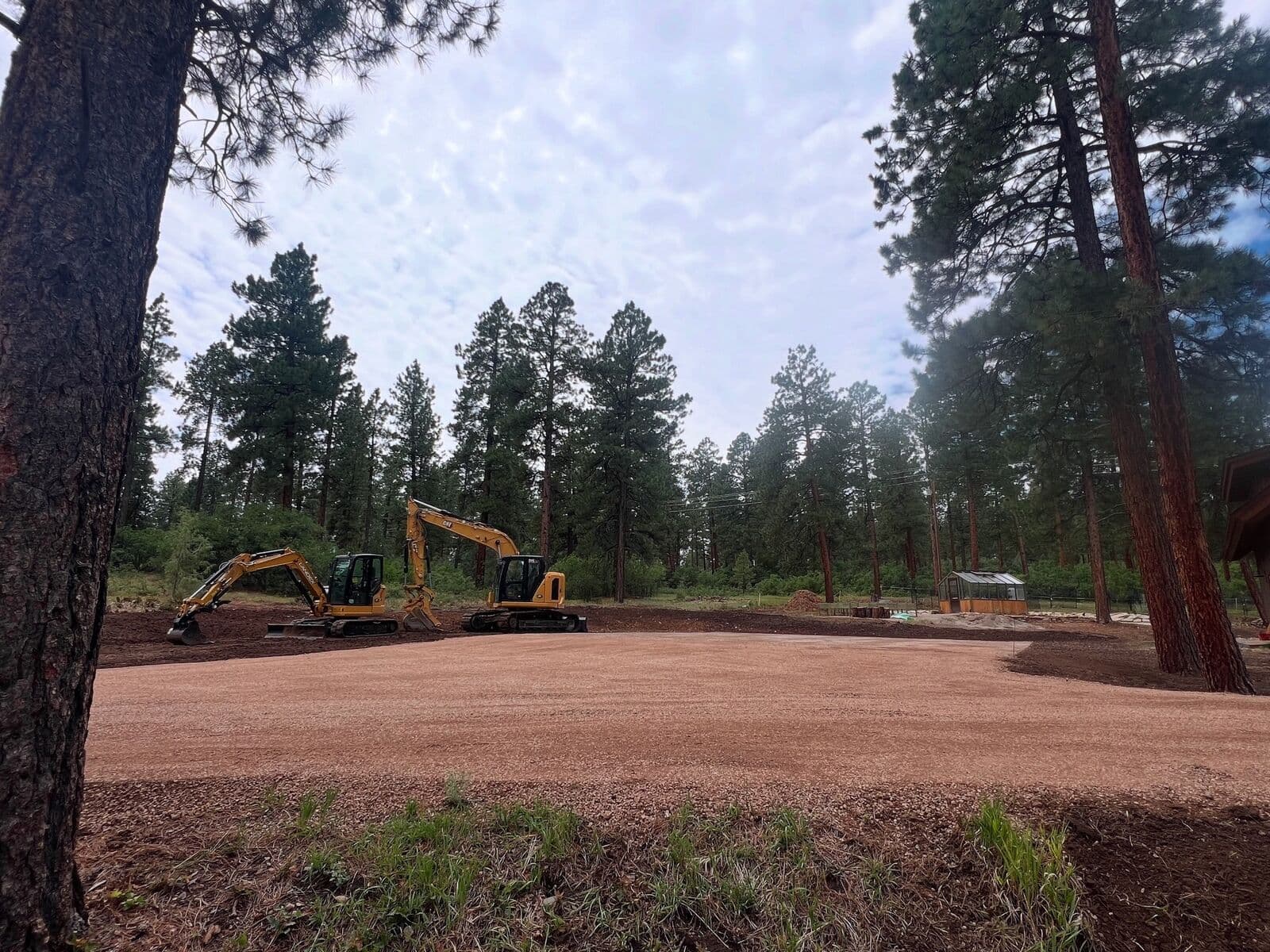 Excavator finishing a cleared and graded mountain lot among ponderosa pines near Durango, Colorado by LandEx Earthworks