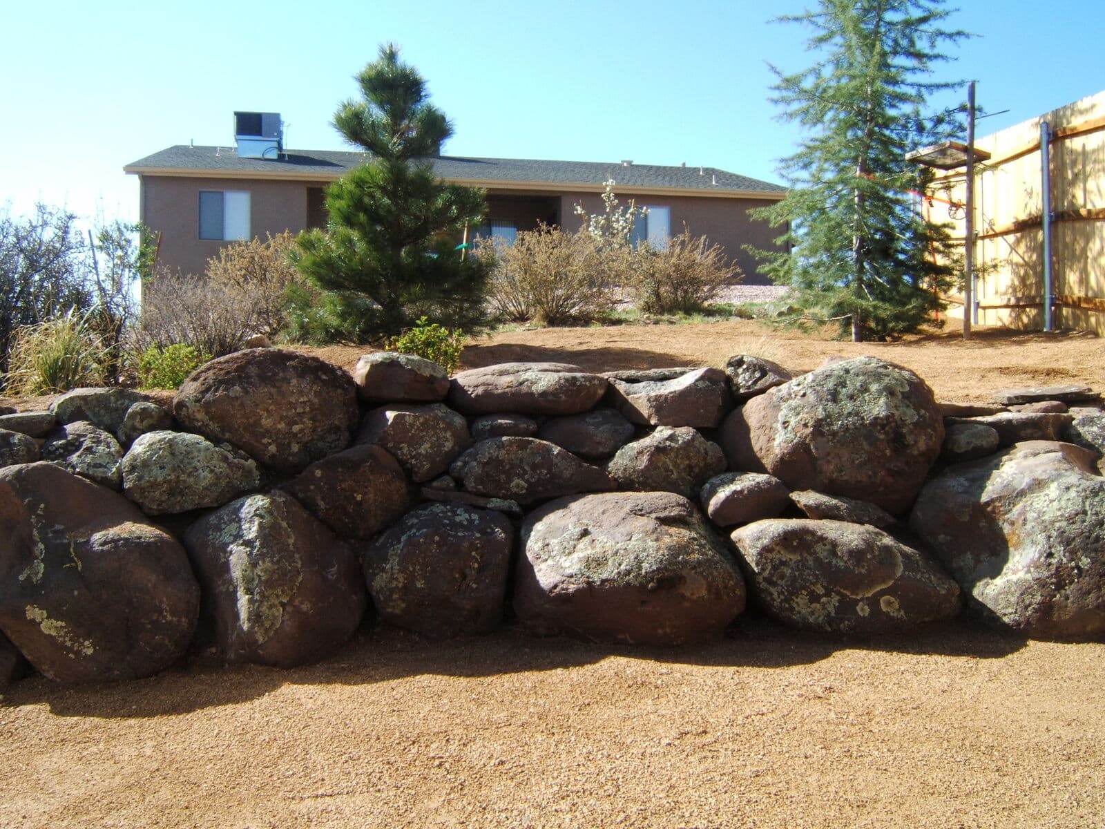 Moss rock boulder retaining wall built in front of a home in Durango, Colorado by LandEx Earthworks