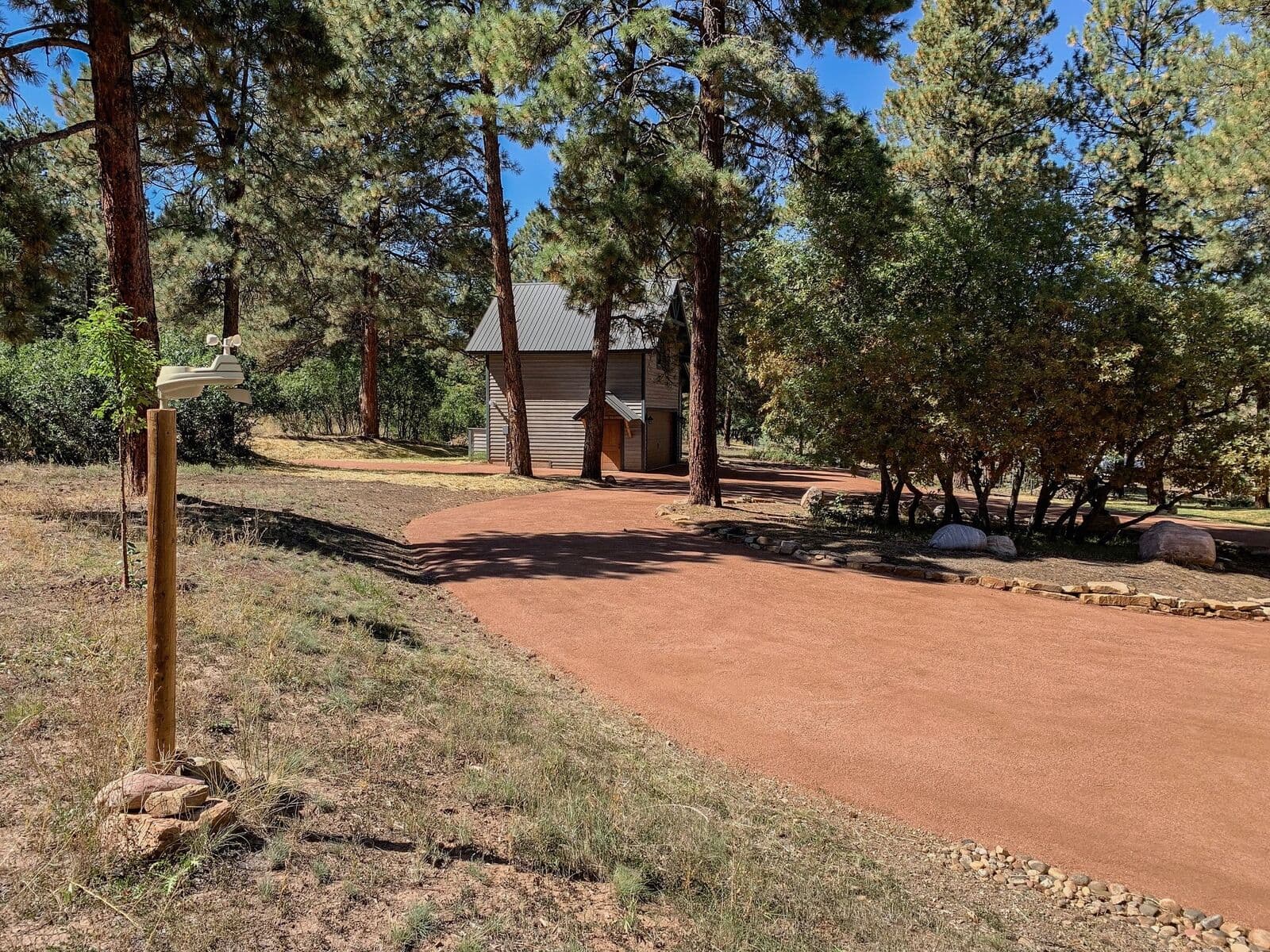 Red cinder driveway installation through mature trees in Durango, Colorado