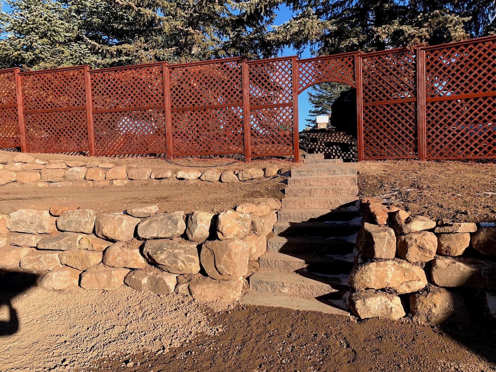 Rock retaining wall with natural stone steps in a fenced garden in Durango, Colorado