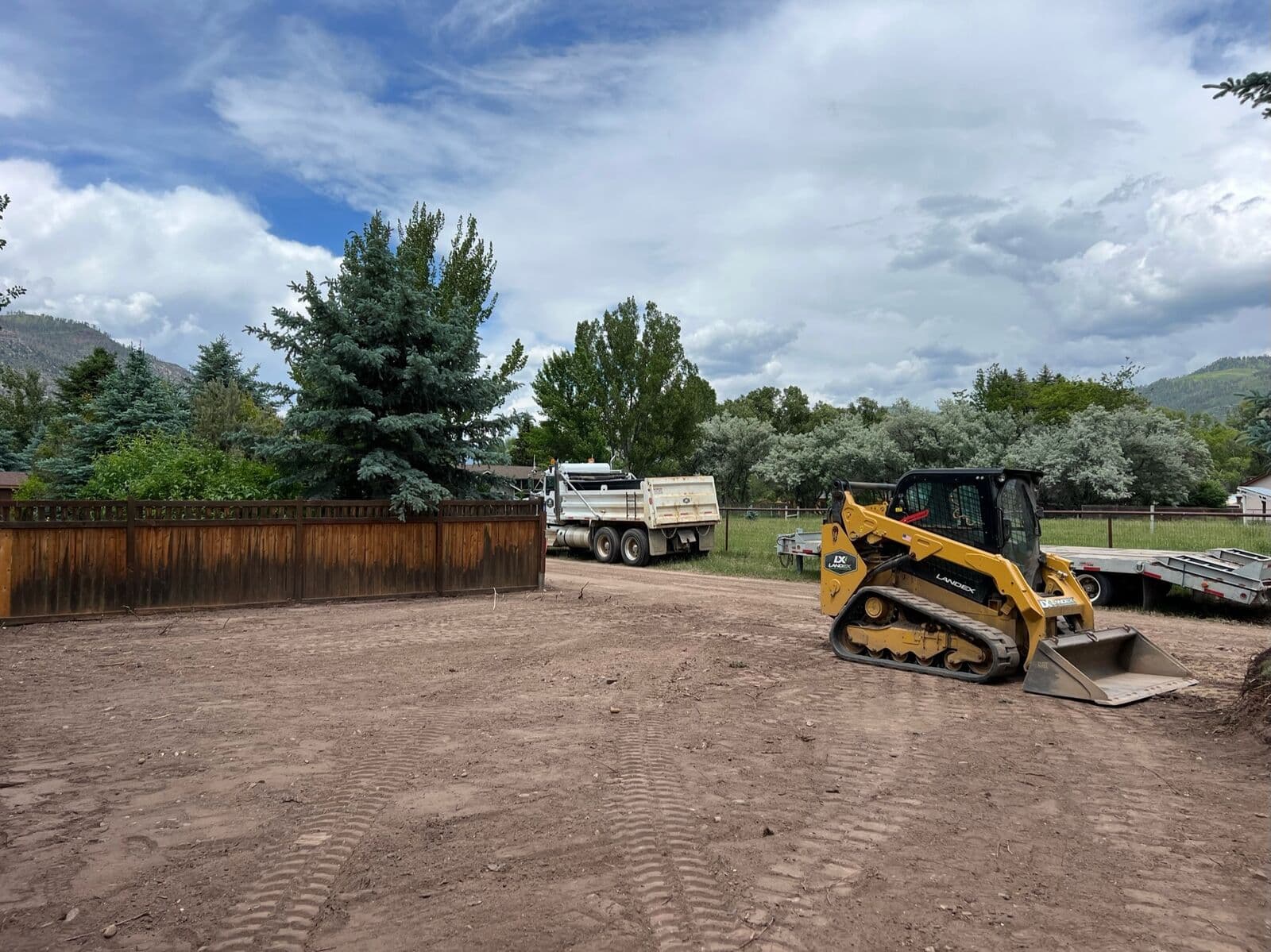 Skid steer and dump truck performing yard grading in Durango, Colorado
